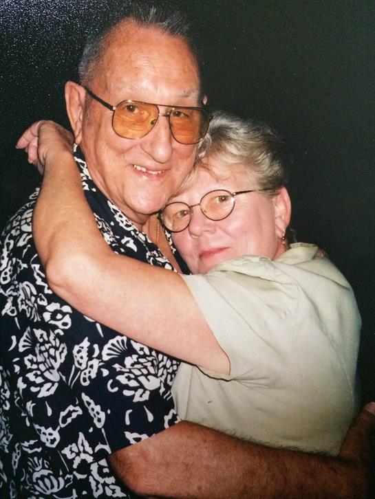 Elderly pair shares a joyful embrace, showcasing their affection and bond during a family gathering.