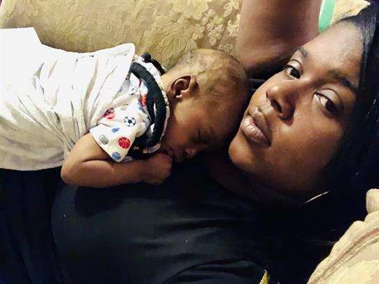 A mother lovingly embraces her sleeping baby, enjoying a quiet moment together on a couch.