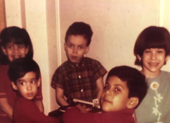 Five kids are indoors, smiling and holding toys as they enjoy time with friends.