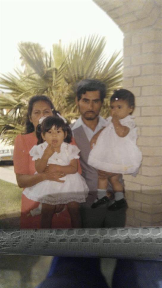 Family poses outdoors with children in white dresses, smiles and joy captured under sunny skies.