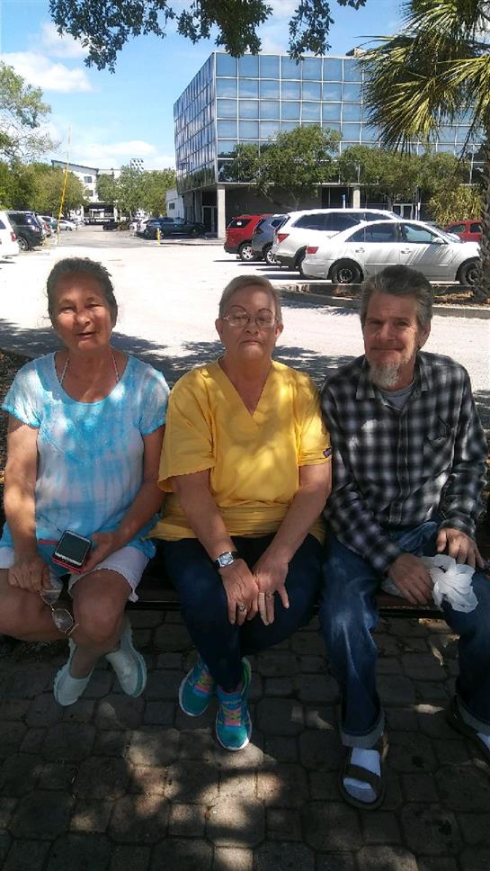 Three individuals sit together on a bench, soaking in the sun and engaging in conversation.
