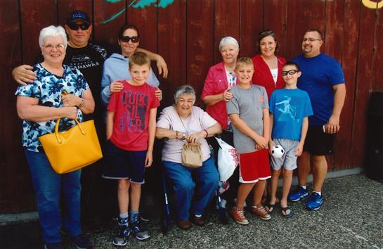 A large group of family members poses happily together in front of a wooden wall.