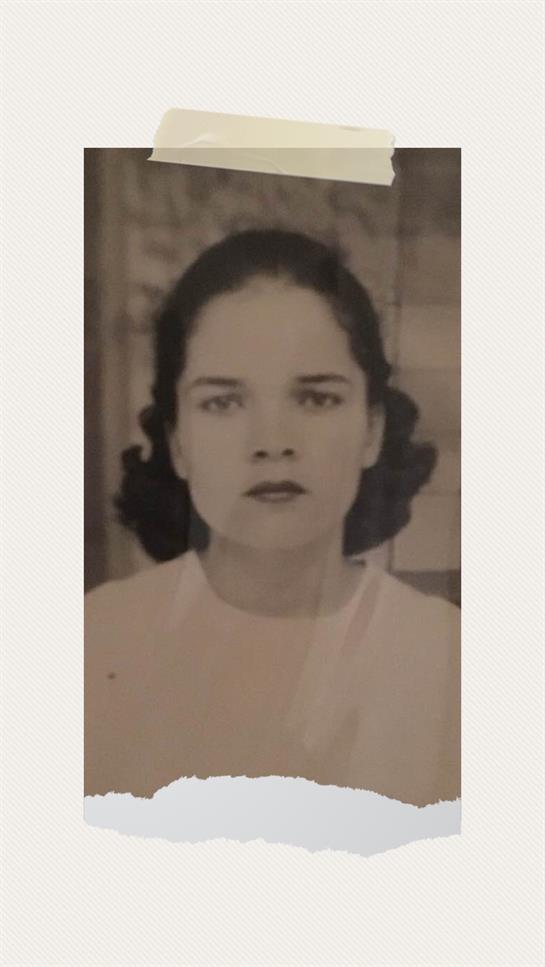 A young woman with dark hair poses seriously against a neutral background in the 1900s.