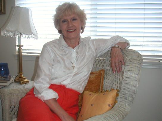 A cheerful woman sits comfortably on a sofa, enjoying the warm light from the window.