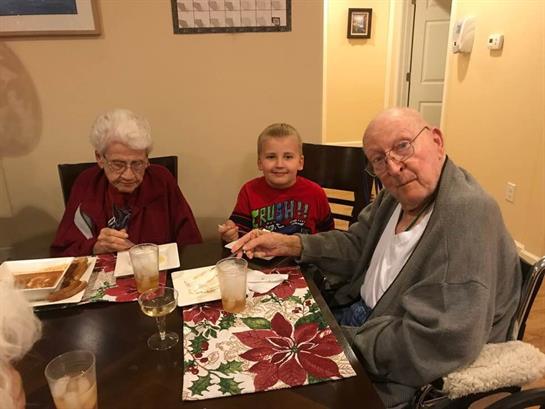 Three family members share food and drinks at the dining table during a holiday gathering.