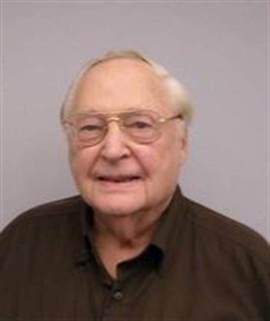 A cheerful elderly man is smiling at the camera while enjoying a leisurely moment indoors.