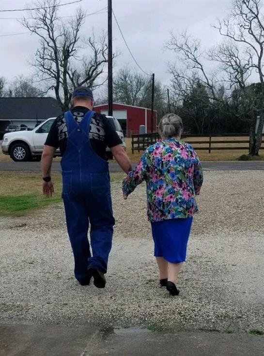 A man and woman stroll together down a gravel path, enjoying each other's company under gray skies.