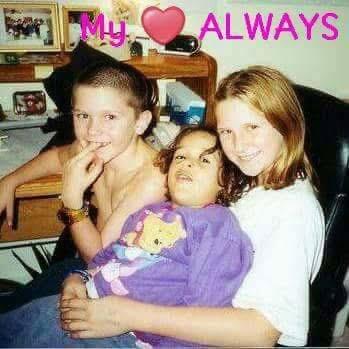Three children share a joyful moment in a comfortable setting, smiling and relaxed while seated.