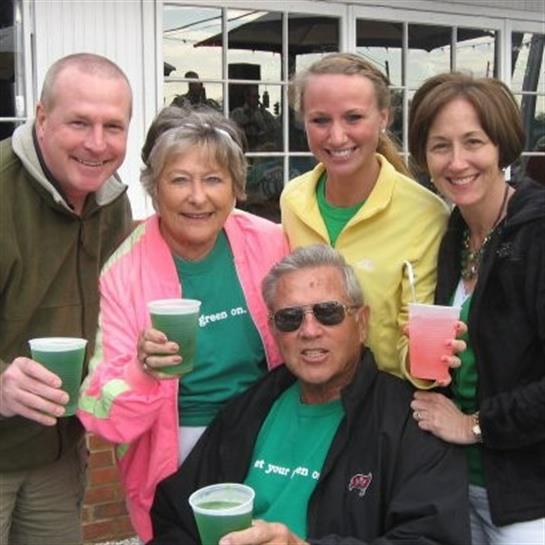 Five friends gather together outdoors holding colorful drinks while smiling and celebrating.