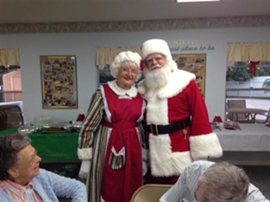 Santa and Mrs. Claus pose together while residents enjoy a festive gathering in December.