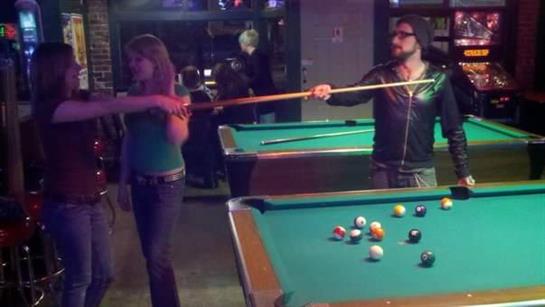 Group of friends engages in competitive billiards while enjoying a night out at the pool hall.