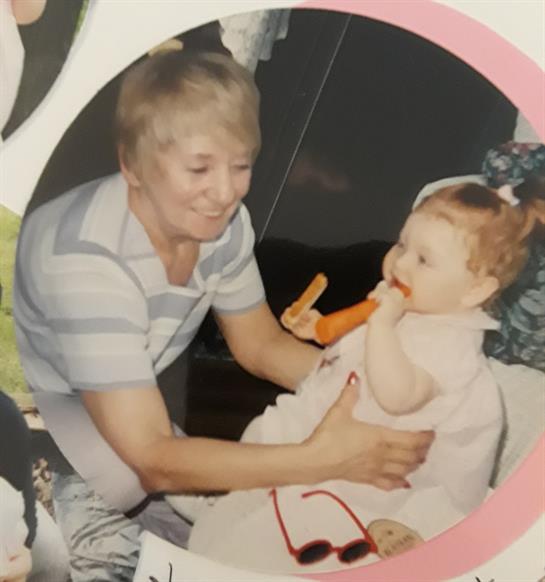 A grandmother lovingly interacts with her grandchild, who is enjoying a carrot in a cozy atmosphere.