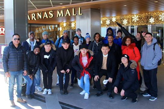 A big group of friends enjoys winter festivities together outside a shopping center.