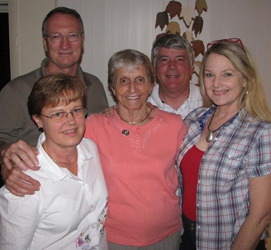 Five family members smile together in a cozy living room filled with warmth and joy.