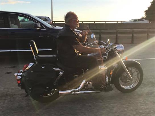 A rider on a motorcycle takes a moment to relax as the sun sets over the highway.