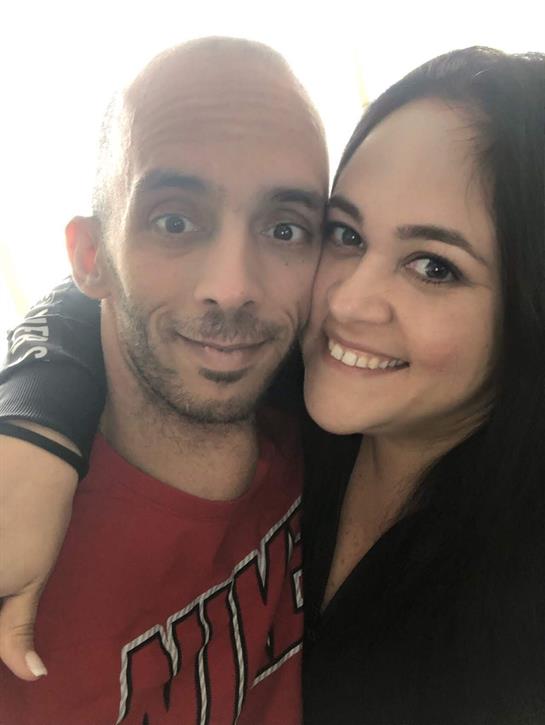 Two people smile widely while embracing each other in a warm and cheerful atmosphere.