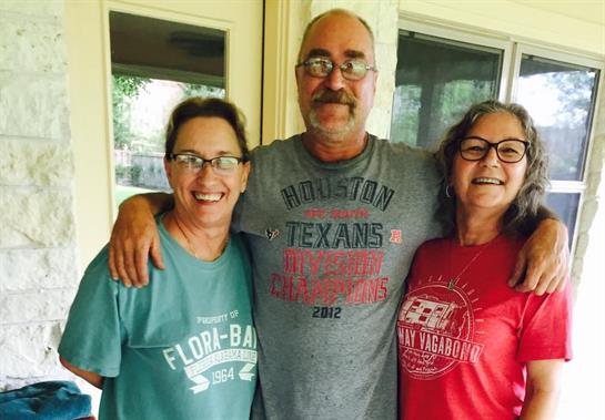 Three friends smile happily together outside, savoring a joyful gathering on a warm day.