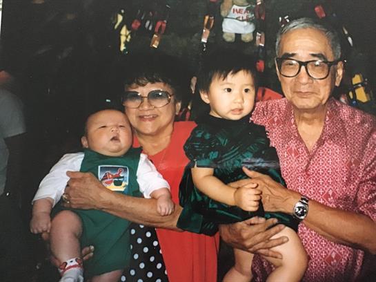 Grandparents hold their grandchildren at a family gathering, showcasing love and togetherness.