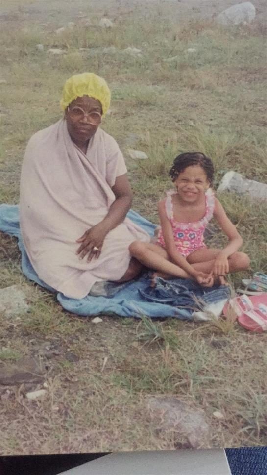 A woman and a girl relax on a blanket in a grassy area, enjoying their time together outdoors.