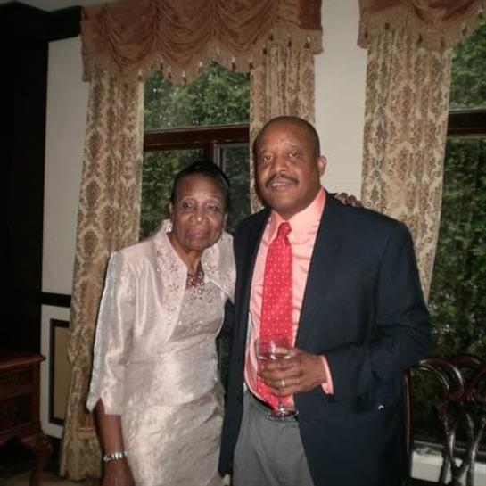 A couple in formal wear smiles, enjoying a sophisticated indoor event together.