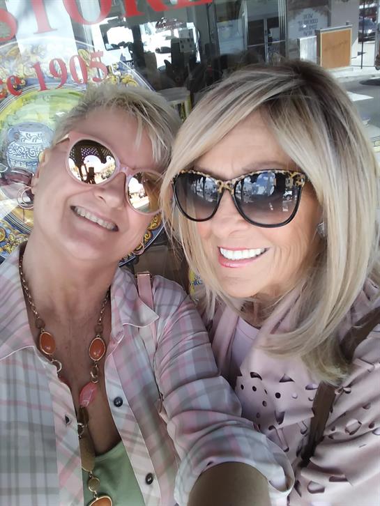 Two smiling friends take a joyful selfie outdoors, capturing their friendship.