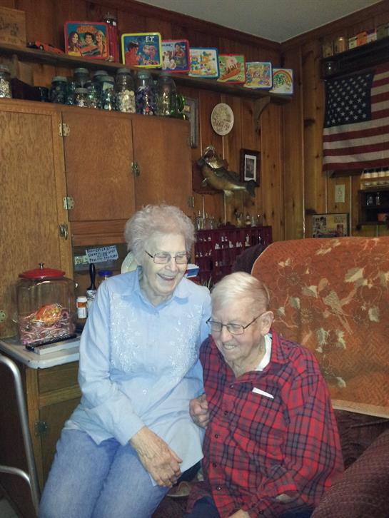 Senior couple smiles and poses together in their comfortable living room filled with warmth.