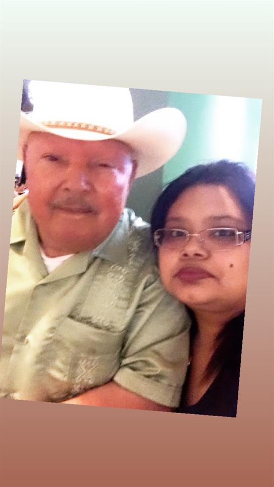 A man in a cowboy hat and a woman with glasses smile happily in a friendly indoor setting.