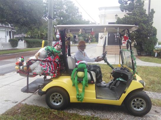 A cheerful individual drives a colorful golf cart adorned with seasonal decorations.