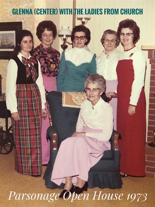 Six women dressed in colorful traditional outfits gather indoors, showcasing their cultural pride.