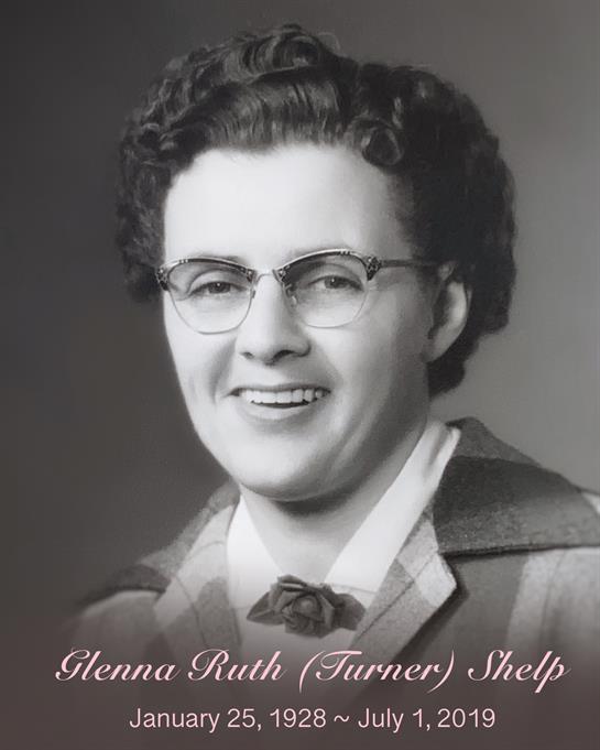 A smiling woman with curly hair and glasses wears mid-1900s formal attire.