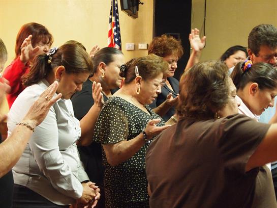 A group of people participates in a heartfelt prayer during a community gathering.