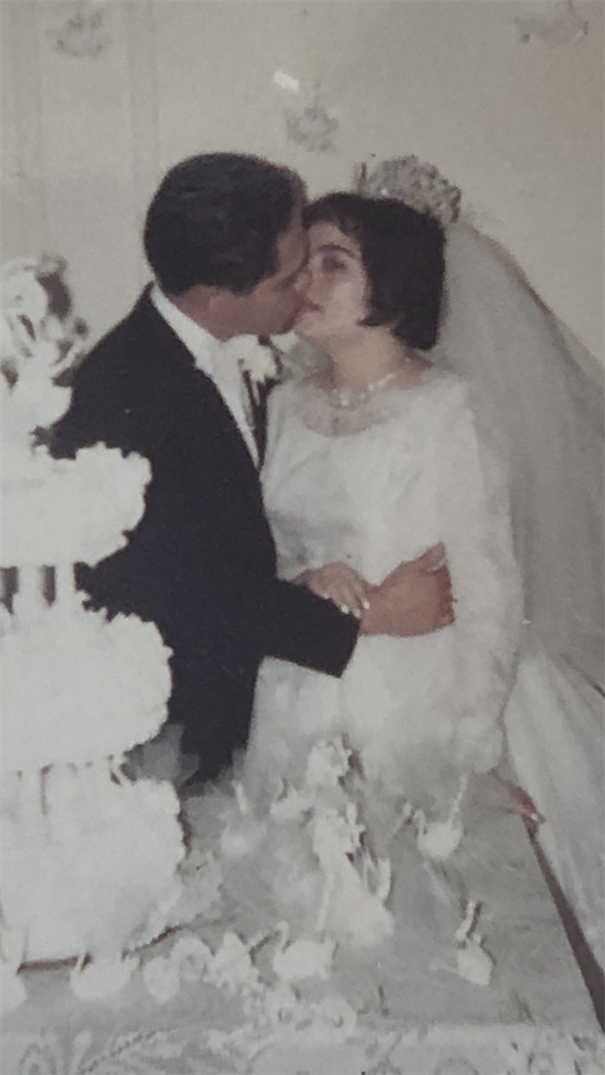 Newlyweds celebrate their love with a romantic kiss at their wedding, surrounded by decorations.