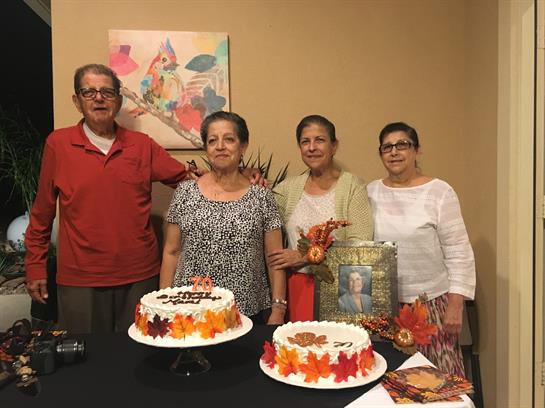 Four family members gather around two elaborately decorated cakes at a festive event.