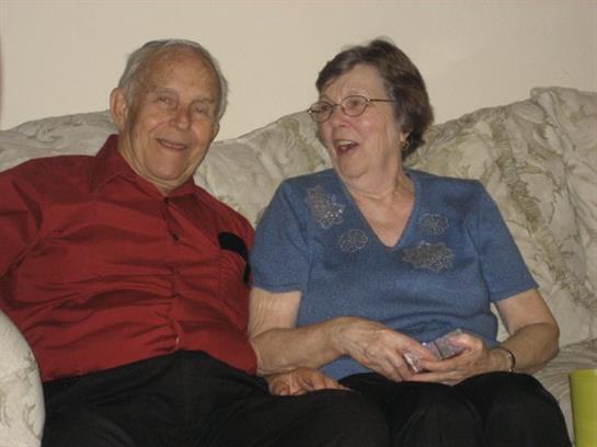 Joyful elderly couple relaxing on a couch, enjoying each other's company and conversation at home.