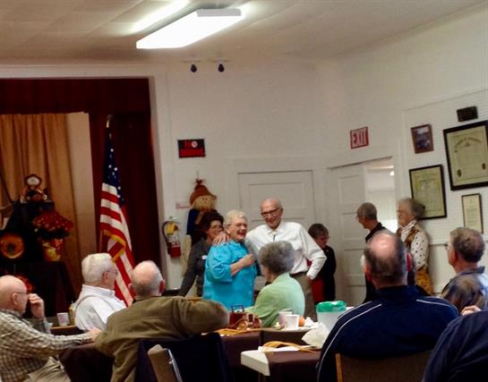 Group of seniors engaged in dancing and socializing at a community center event.