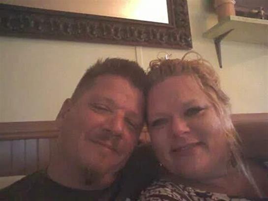 Two people share a close, affectionate moment, smiling happily in a comfortable indoor space.