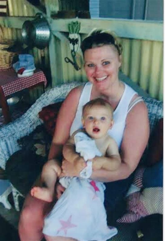 A joyful woman embraces a baby in a welcoming outdoor space surrounded by decor.