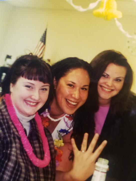 Three women smile and pose playfully during a lively celebration, showcasing excitement.