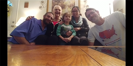 Family members gather together, smiling and enjoying each other's company in a warm setting.