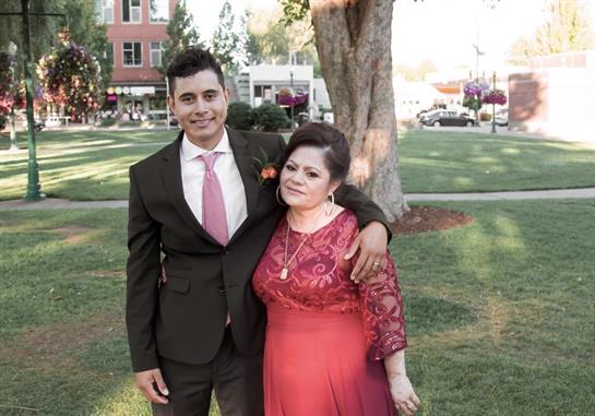 Smiling young man stands with woman in red, both enjoying a joyful moment in the park.