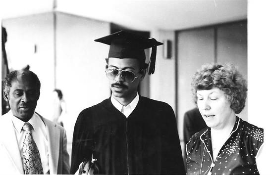 Students celebrate graduation in vintage attire, showcasing joy in a university hallway.