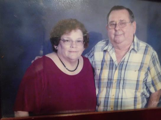 A couple stands closely together smiling, celebrating their love during a family event.
