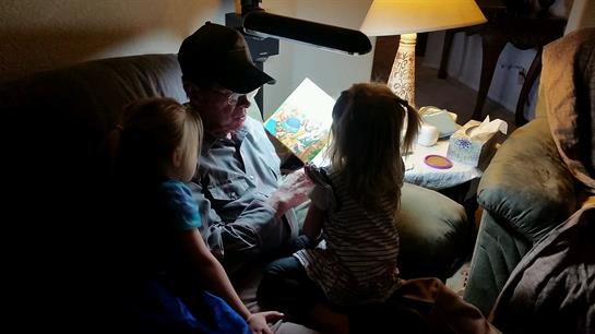 A grandfather engages his grandchildren with a captivating story in a warm-lit living room.