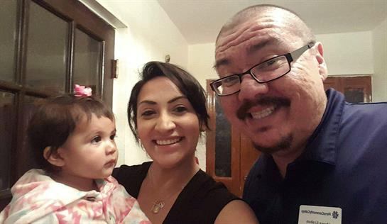 A happy family poses together in a home, celebrating a cherished moment with their baby.