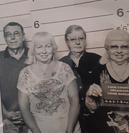 Four people stand together in a mugshot, smiling and sharing a lighthearted moment.