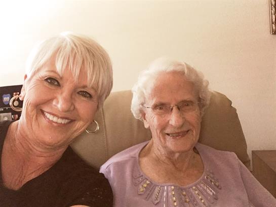 Two women share smiles and laughter in a warm, inviting living room while spending time together.