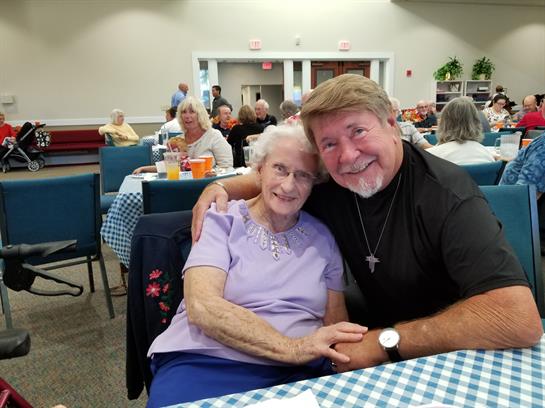 Two friends share joy and affection at a community event filled with laughter and connection.