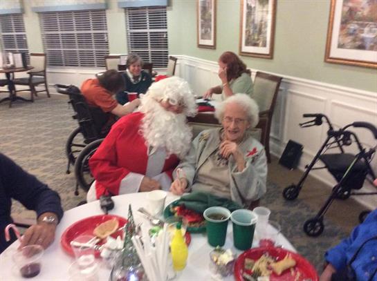 Seniors enjoy a Christmas event with festive decorations, food, and Santa at a community center.