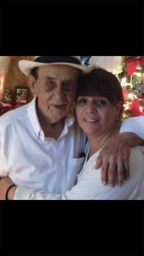 A joyful moment between a man and a woman, embracing in front of a decorated Christmas tree.