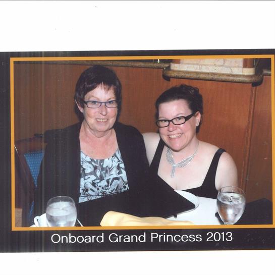 Two women sit at a table, enjoying dinner on a cruise in 2013, surrounded by drinks and smiles.